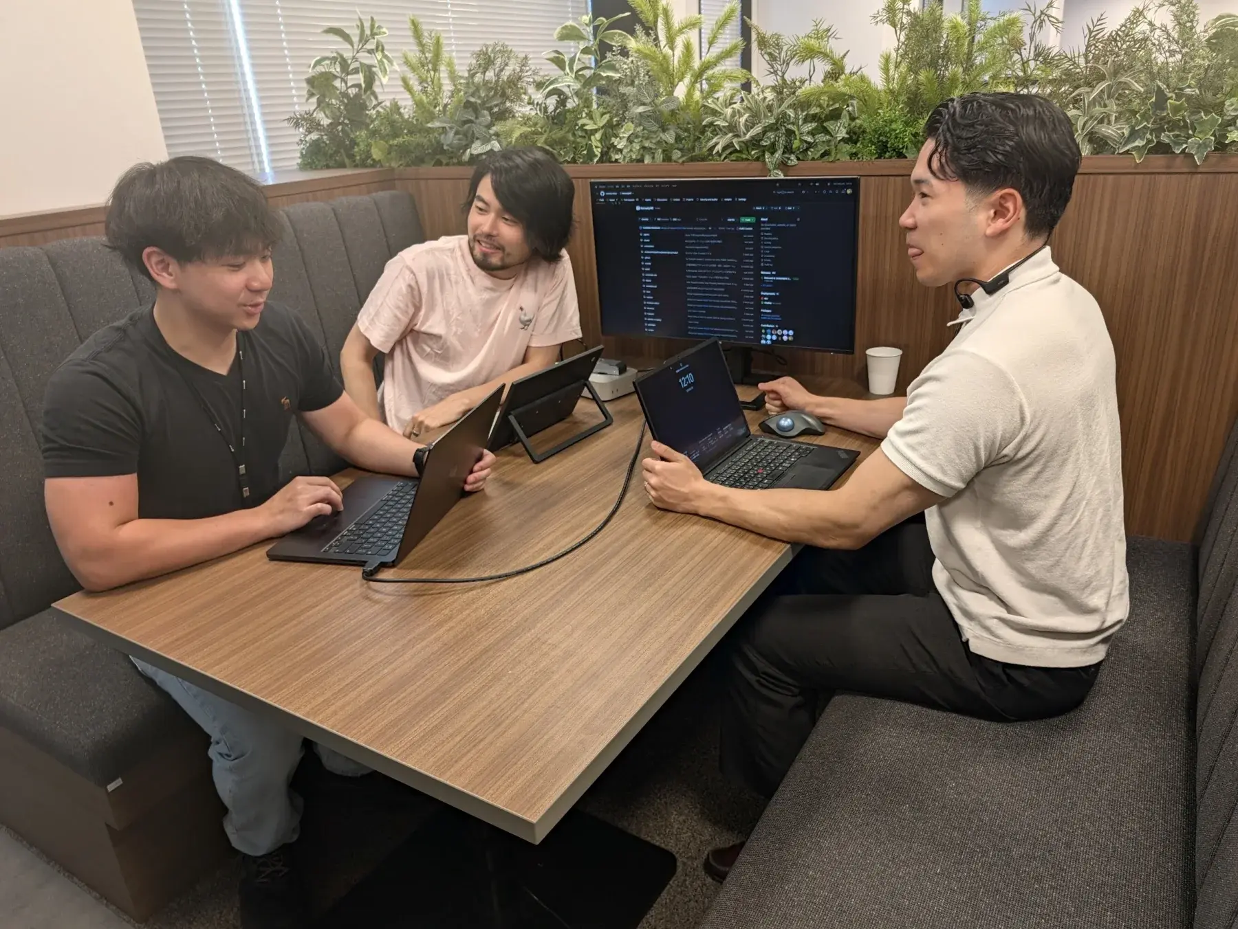 エンジニア3人がノートPCを囲んで話す様子